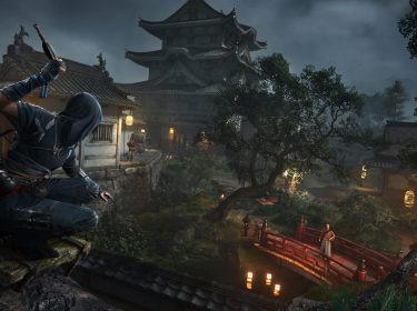 Auf dem Bild aus dem Assassin's Creed Shadows Test ist ein vermummter Ninja in dunkler Kleidung zu sehen, der auf einem Baumast hockt und eine Waffe zum Wurf bereithält. Die Szenerie zeigt eine traditionelle japanische Festung in einer stimmungsvollen, nächtlichen Umgebung mit Laternenlicht. Im Hintergrund steht eine Wache auf einer roten Brücke, während weitere Patrouillen im befestigten Anwesen unterwegs sind.