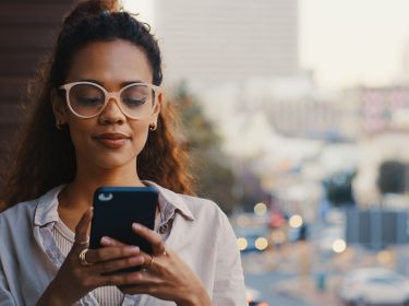 Eine junge Frau hält ein Smartphone in der Hand