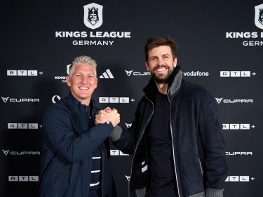 Auf dem Bild zur Kings League Germany stehen die ehemaligen Fußballstars Bastian Schweinsteiger und Gerard Piqué vor einer Sponsorenwand der Kings League Germany. Beide lächeln in die Kamera und geben sich sportlich die Hand. Die Szene wirkt freundschaftlich und professionell, passend zum sportlichen Auftakt des neuen Fußballformats in Deutschland.