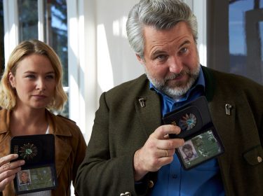 Eva Winter (Vanessa Eckart) und Kommissar Anton Stadler (Dieter Fischer) zeigen vor einem Haus ihre Polizeimarken.