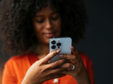 Schwarze Frau hält ein iPhone in den Händen.