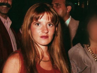 Angi - (K)eine perfekte Mörderin: Eine junge Frau mit roten Lippen und roten Top schaut ernst in die Kamera, umgeben von weiteren Personen auf einer Veranstaltung.