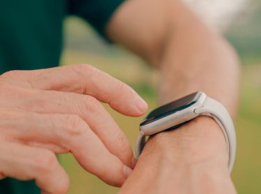 Frau tippt auf die Apple Watch an ihrem Handgelenk.