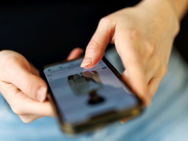 Eine junge Frau benutzt die Instagram-App auf ihrem Smartphone.