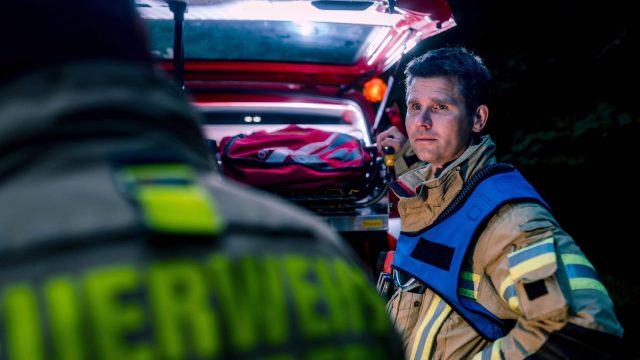 Berufsfeuerwehrmann steht vor Mehrzweckfahrzeug