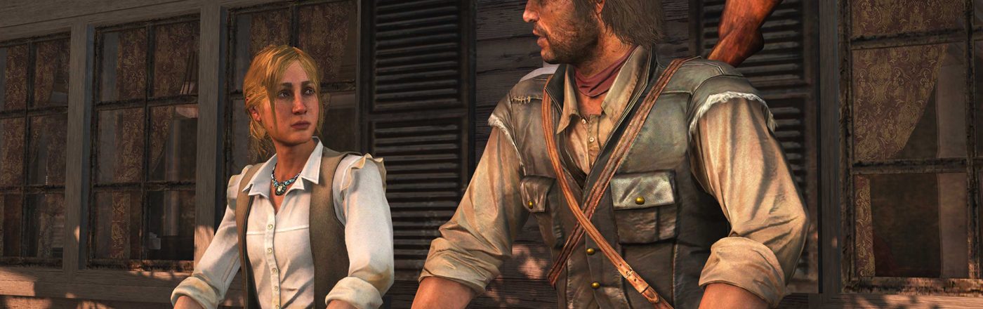 Im Screenshot aus dem Spiel Red Dead Redemption sind John Marston und seine Frau Abigail auf einer Holzveranda zu sehen. John trägt einen Cowboyhut, Handschuhe und eine Lederweste mit Gewehr auf dem Rücken, während Abigail in heller Bluse und Weste ernst schaut. Die Szene vermittelt eine ruhige, ernste Stimmung.