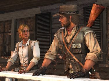 Im Screenshot aus dem Spiel Red Dead Redemption sind John Marston und seine Frau Abigail auf einer Holzveranda zu sehen. John trägt einen Cowboyhut, Handschuhe und eine Lederweste mit Gewehr auf dem Rücken, während Abigail in heller Bluse und Weste ernst schaut. Die Szene vermittelt eine ruhige, ernste Stimmung.