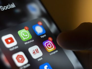 Ein Handydisplay zeigt die Icons verschiedener Apps, darunter WhatsApp und Signal.