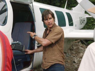 Tom Cruise als Barry Seal steht vor einem offenen Flugzeug.