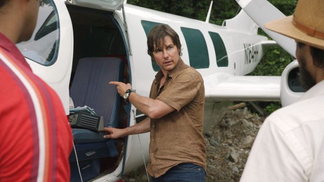 Tom Cruise als Barry Seal steht vor einem offenen Flugzeug.