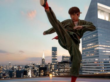 In dieser Szene aus dem Film Karate Kid: Legends ist Ben Wang als Karate Kid auf einem Hochhausdach vor der Skyline einer Großstadt zu sehen. Mit einem präzisen Tritt in der Luft und ernstem Gesichtsausdruck verkörpert er Entschlossenheit und Fokus.