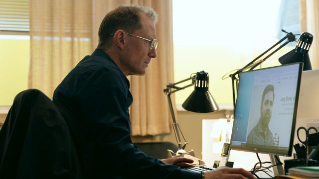 Peter Eggers sitzt in einer Szene von "Genombrottet" vor dem Computer.