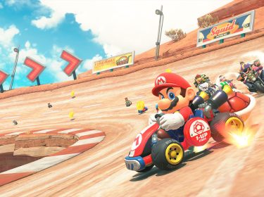 Auf dem Bild in dem Artikel zum Mario Kart World-Test führt Mario das Rennen auf einer Rennstrecke an. Er sitzt in einem roten Kart. Hinter ihm folgen weitere bekannte Fahrer:innen. Goldene Münzen und Streckenhinweise unterstreichen das typische Mario-Kart-Design.