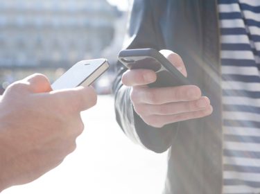 Zwei Hände, die zwei Smartphones aneinanderhalten.