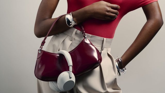 Frau trägt Sony-Kopfhörer über ihrer Handtasche.