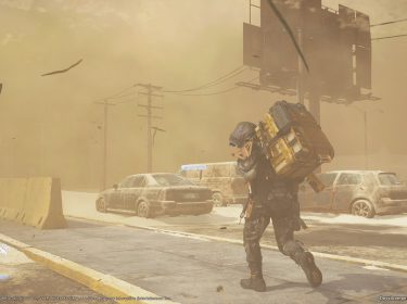 Auf diesem Screenshot aus Death Stranding 2: On the Beach kämpft der Lieferant in schwerer Ausrüstung gegen einen heftigen Sandsturm an. Er geht gebückt und schützt sein Gesicht, während hinter ihm verlassene, verrostete Autos und eine staubige Straße eine postapokalyptische Stimmung erzeugen.