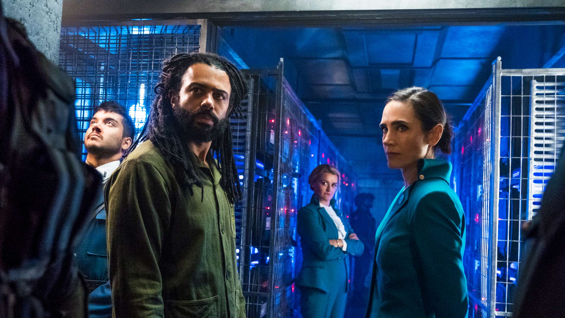 In den GigaTV-Highlights im Juli 2025 siehst du ein Bild aus der Serie Snowpiercer: Daveed Diggs steht vorne links in einem grünen Outfit, Jennifer Connelly rechts in einer türkisfarbenen Uniform. Beide blicken ernst nach vorn.