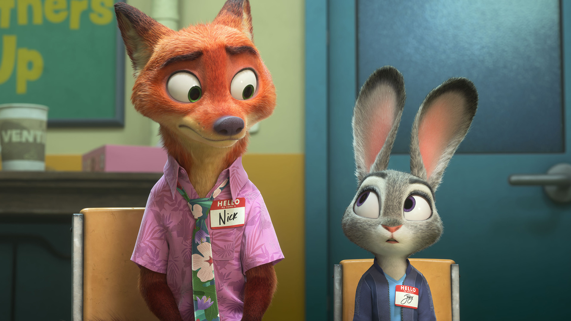Auf dem Bild zu Zoomania 2 sitzen Nick Wilde und Judy Hopps auf Stühlen. Nick, ein rot-orangefarbener Fuchs im Hawaiihemd, schaut verlegen zur Seite, während Judy, eine graue Häsin in Uniform, ihn überrascht ansieht. Beide tragen Namensschilder.