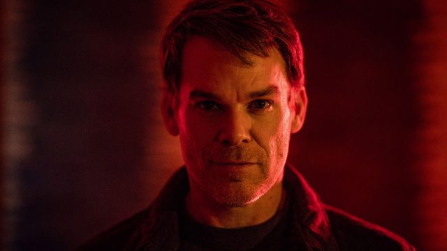 Im Streaming-Highlights-Artikel ist ein Bild aus der Serie Dexter: Wiedererwachen zu sehen. Im Zentrum steht Michael C. Hall in seiner Rolle als Dexter Morgan. Er blickt direkt in die Kamera, sein Gesicht wird von einem intensiven, rötlichen Licht beleuchtet, das eine düstere und spannungsgeladene Stimmung erzeugt.