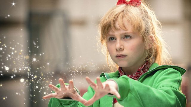 In dieser Szene aus Bibi Blocksberg – Das große Hexentreffen ist NALA als Bibi Blocksberg zu sehen. Sie trägt eine grüne Jacke und ein rotes Haarband, während sie konzentriert mit ausgestreckten Händen magische Funken erzeugt. Die Lichtpartikel unterstreichen die zauberhafte Stimmung und Bibis Entschlossenheit in einem wichtigen Moment.