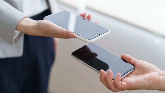 Zwei Hände zeigen sich gegenseitig das Display eines Smartphones