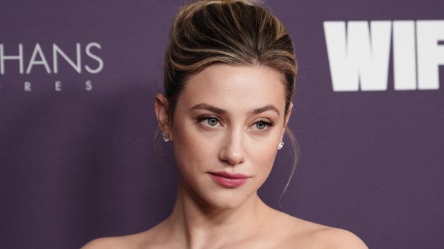 Auf dem Bild in dem Artikel zum The Love Hypothesis-Film ist Lili Reinhart vor einer violetten Pressewand zu sehen. Sie blickt leicht zur Seite
