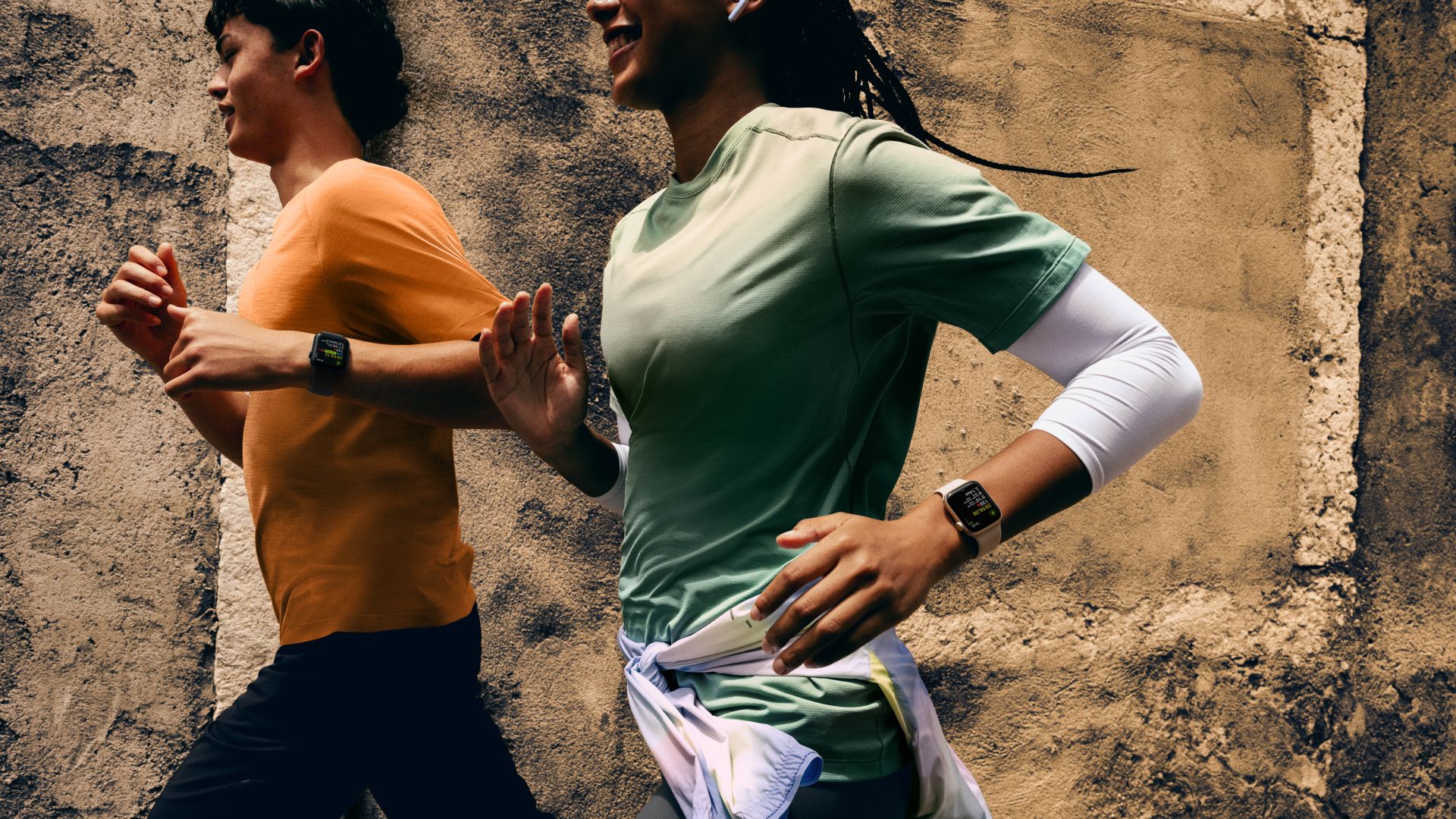 Zwei Läufer mit Apple Watch SE am Handgelenk laufen durch das Bild.