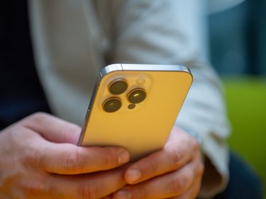 Ein Mann hält ein iPhone in den Händen.