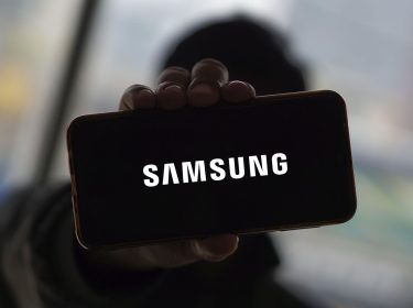 Mann hält Smartphone hoch, auf dem das Samsung-Logo zu sehen ist.