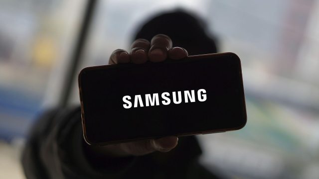 Mann hält Smartphone hoch, auf dem das Samsung-Logo zu sehen ist.