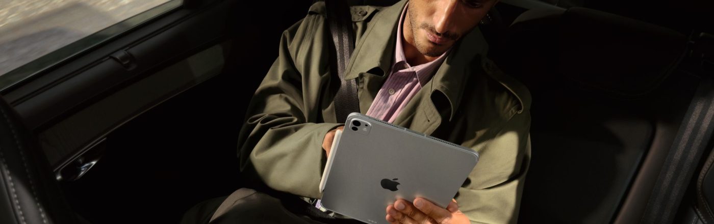 Mann sitzt im Auto und schaut auf das iPad Pro in seinen Händen.