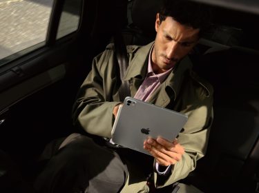Mann sitzt im Auto und schaut auf das iPad Pro in seinen Händen.
