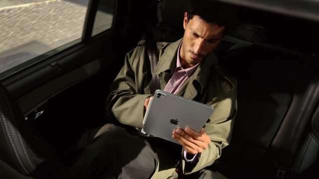 Mann sitzt im Auto und schaut auf das iPad Pro in seinen Händen.