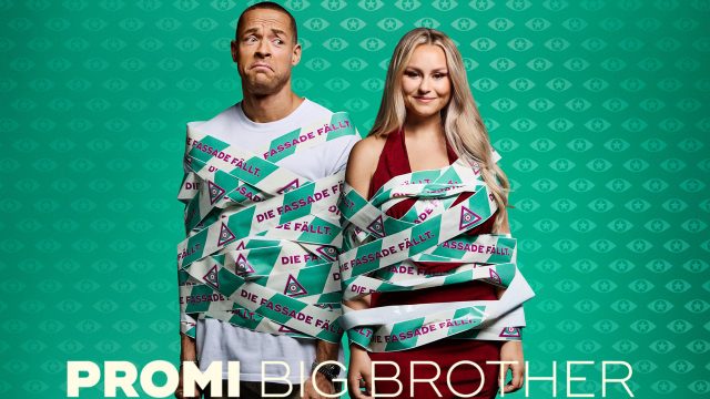 Auf dem Bild zu Promi Big Brother 2025 stehen Andrej Mangold und Sarah-Jane Wollny nebeneinander, beide mit Band umwickelt, auf dem „Die Fassade fällt.“ steht. Andrej blickt skeptisch, Sarah-Jane lächelt.