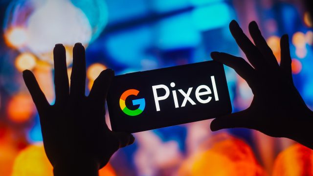 Als Schatten dargestellte Hände halten auf einem Event ein Smartphone mit Pixel-Logo hoch.