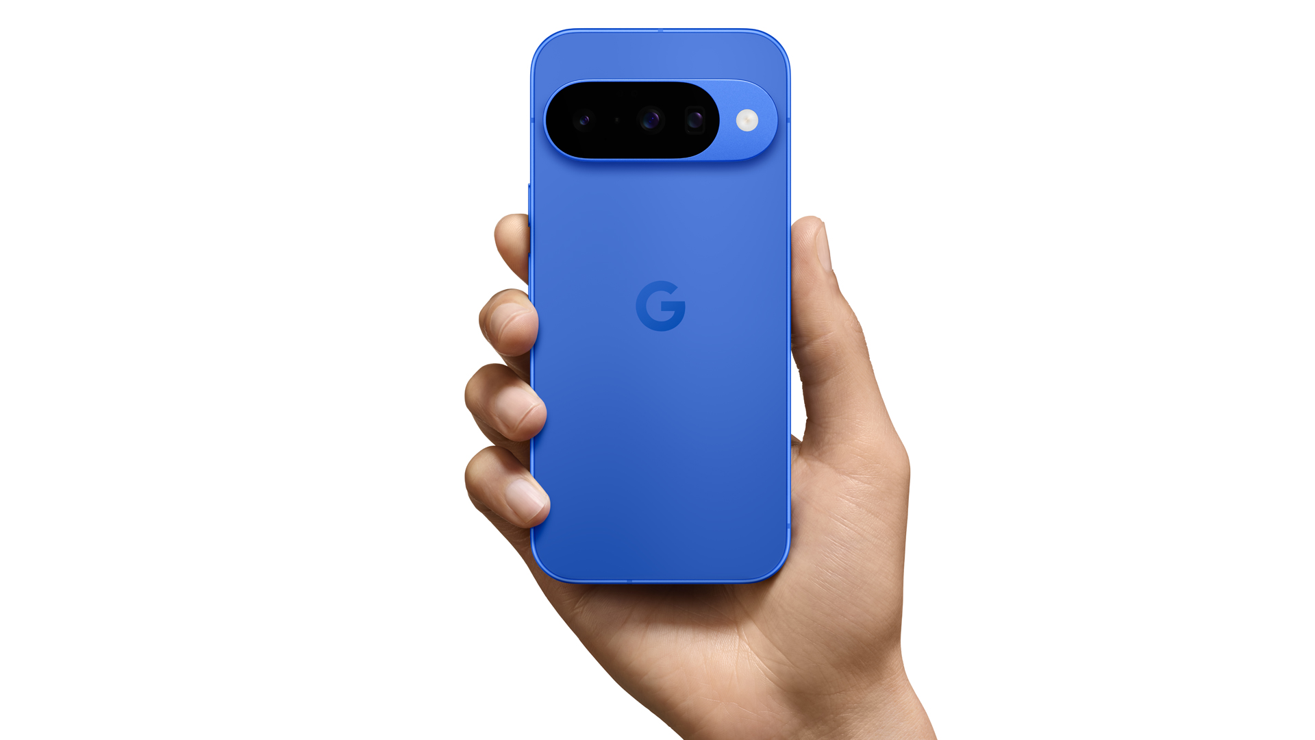 Auf dem Produktbild aus der Google Pixel 10-Reihe hält eine Hand das Google Pixel 10 in der Farbe Indigo (Blau). Zu sehen ist die Rückseite mit der markanten Kameraleiste, die drei Linsen und einen Blitz umfasst. Das matte Finish und das eingravierte „G“-Logo in der Mitte unterstreichen das minimalistische Design des Smartphones.