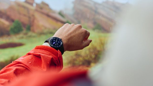 Mann schaut im Regen auf die Pixel Watch 4 an seinem Handgelenk.