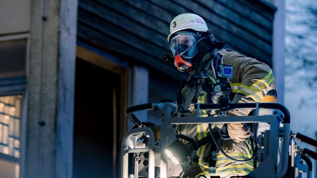 Ein Feuerwehrmann in "Feuer und Flamme" bei einem Einsatz auf der Drehleiter.