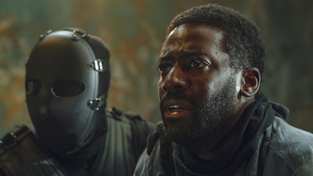 Bild aus der Serie Hostage: Ein Mann wird als Geisel von einer maskierten Person abgeführt.