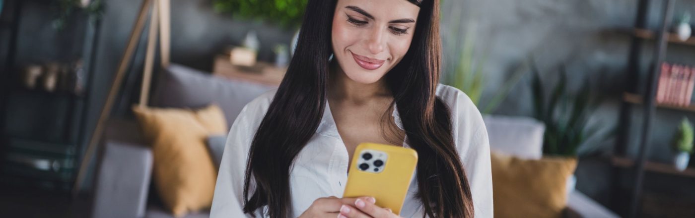 Junge Frau schaut auf ein iPhone mit gelber Hülle.