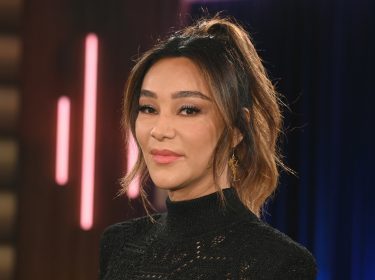 Dieses Symbolbild zu Villa der Versuchung 2026 zeigt Moderatorin Verona Pooth in einem schwarzen, hochgeschlossenen Oberteil mit feinem Muster. Sie steht vor einem Studiolicht-Hintergrund mit dunklen Blau- und Rosatönen. Ihr Blick ist ruhig und selbstbewusst, das Bild vermittelt eine elegante und professionelle Stimmung.