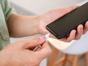 Das Bild im Artikel zum Akku wechseln beim Samsung zeigt, wie eine Person ein USB-C-Ladekabel an ein schwarzes Smartphone anschließt – stellvertretend für einen Akkuwechsel oder einen Ladevorgang.