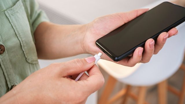 Das Bild im Artikel zum Akku wechseln beim Samsung zeigt, wie eine Person ein USB-C-Ladekabel an ein schwarzes Smartphone anschließt – stellvertretend für einen Akkuwechsel oder einen Ladevorgang.