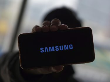 Eine Hand hält ein Smartphone hoch, auf dem das Samsung-Logo zu sehen ist.