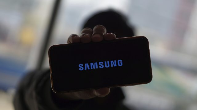 Eine Hand hält ein Smartphone hoch, auf dem das Samsung-Logo zu sehen ist.