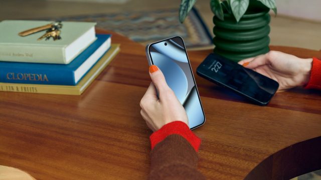 Eine Hand hält das Google Pixel 10 Pro, im Hintergrund ein dunkler Holzschreibtisch mit Büchern.