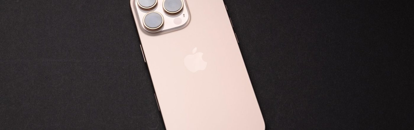 Das iPhone 16 Pro in der Farbe Wüstensand liegt auf einer schwarzen Oberfläche.