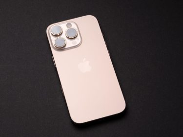 Das iPhone 16 Pro in der Farbe Wüstensand liegt auf einer schwarzen Oberfläche.