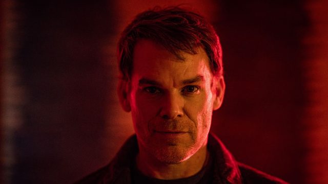 Auf dem Bild zu Dexter: Wiedererwachen ist Dexter Morgan zu sehen, gespielt von Michael C. Hall. Er blickt ernst und direkt in die Kamera, umgeben von dramatischem Rotlicht, das eine düstere und spannungsgeladene Stimmung erzeugt. Das Bild vermittelt eine intensive Atmosphäre, passend zur düsteren Serie.