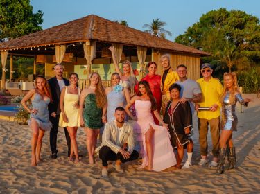 Auf dem Bild zur Show Kampf der RealityAllstars posieren zahlreiche Reality-TV-Persönlichkeiten barfuß am Sandstrand vor einer tropischen Villa. Zu sehen sind u.a. Georgina Fleur, Sandy Fähse, Yeliz Koc, Tayisiya und Yana Morderger, Serkan Yavuz, Kader Loth, Giuliana Farfalla, Kate Merlan, Sam Dylan, Narumol, Paco Herb, Prinz Frédéric von Anhalt und Loona. Die Stimmung wirkt ausgelassen und sommerlich.